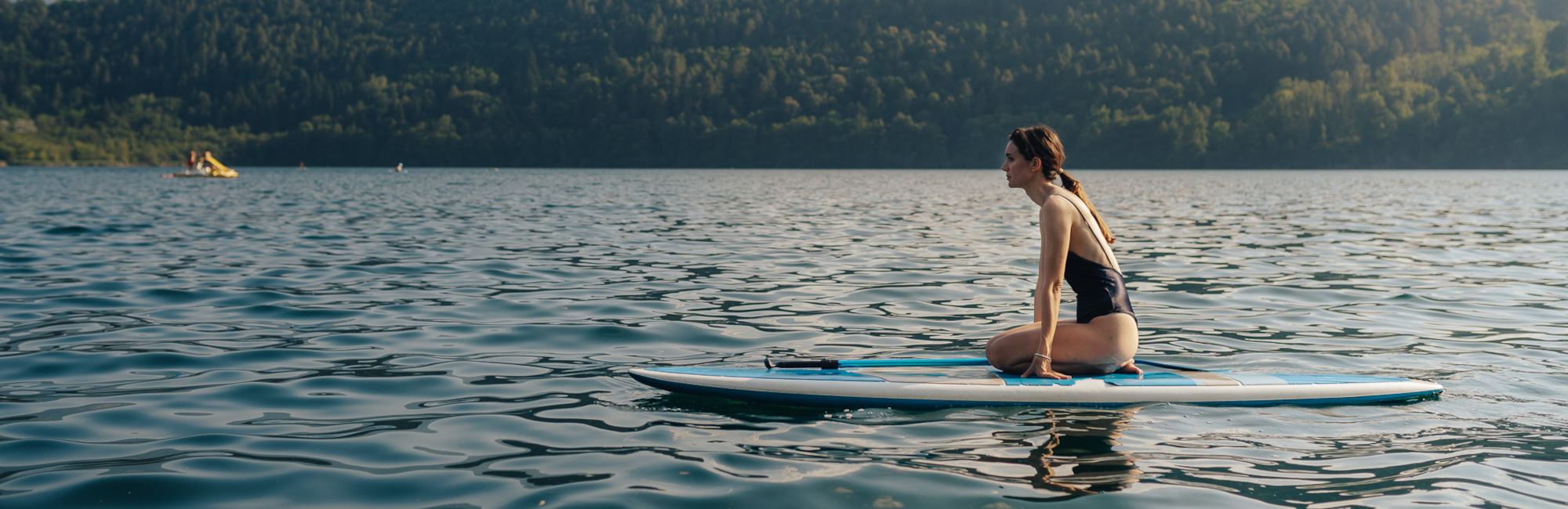 Donna sul paddle al Lago di Levico con sfondo panoramico