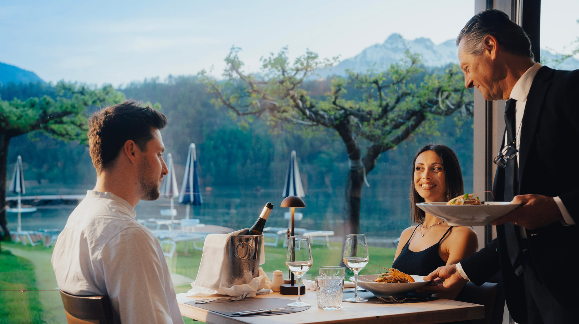 Cameriere che serve la cena a una coppia nel ristorante con vista sul Lago di Levico