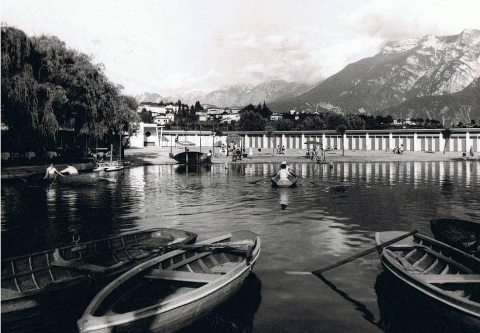 Immagine storica del Lago di Levico con barche ormeggiate, vista sulle montagne e sul vecchio stabilimento balneare