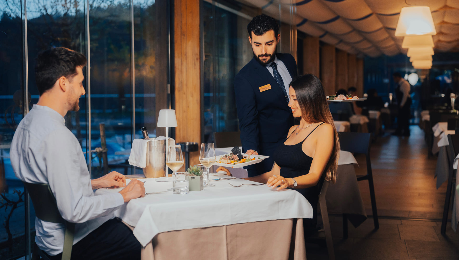 Cameriere serve piatti gourmet a una coppia nel ristorante elegante.